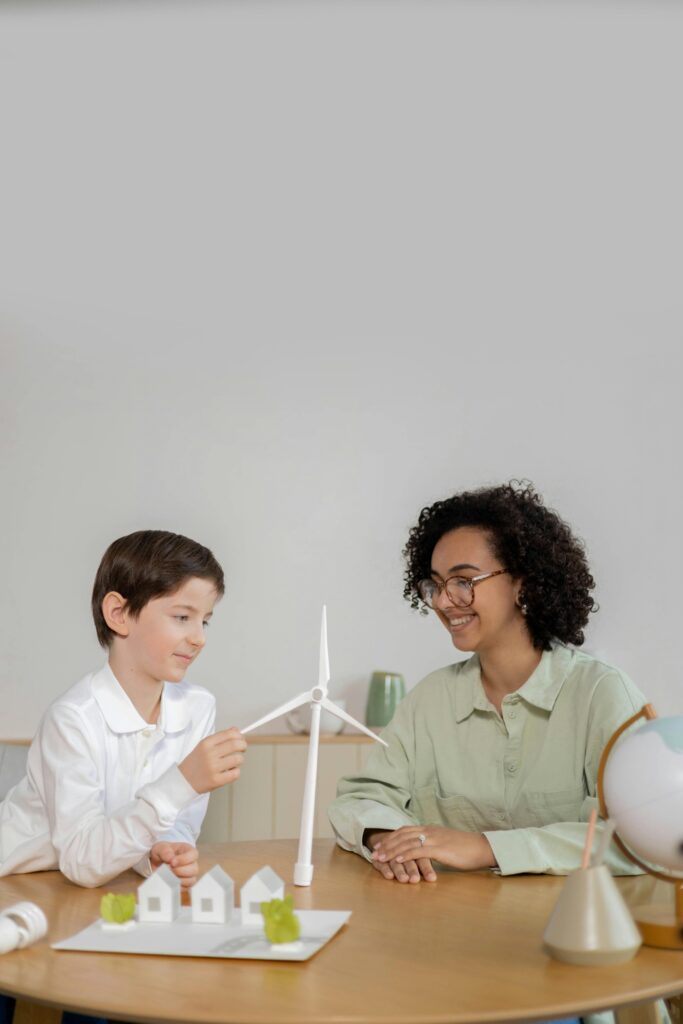 Child and teacher exploring wind energy with turbine model in classroom. Green technology innovations